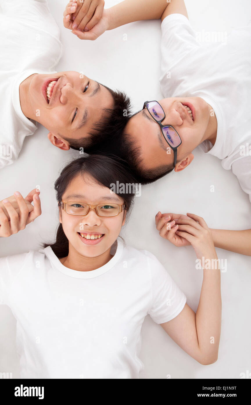Teenagers lying on back and smiling at the camera together Stock Photo