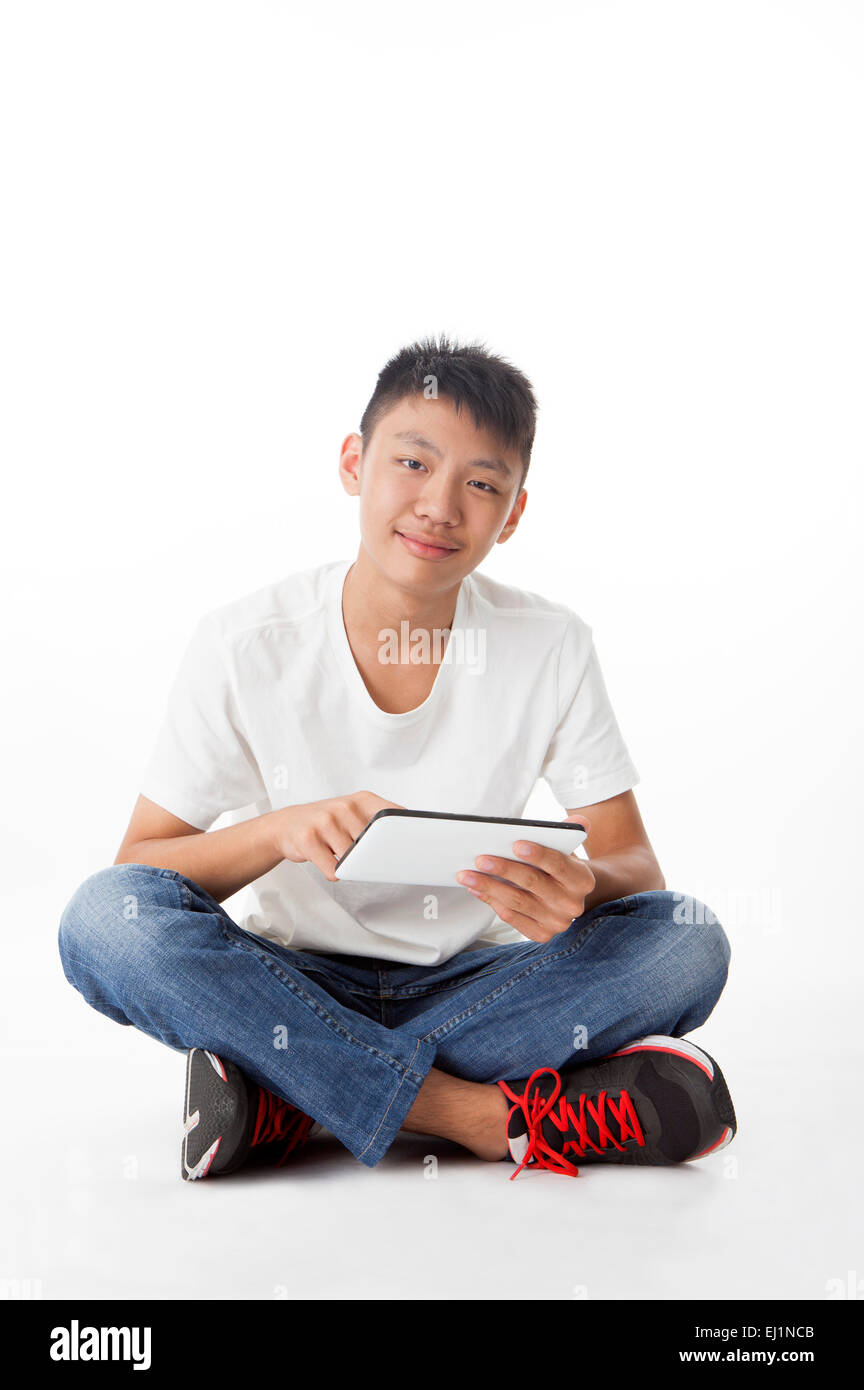 Teenage boy sitting and holding touchpad with smile Stock Photo