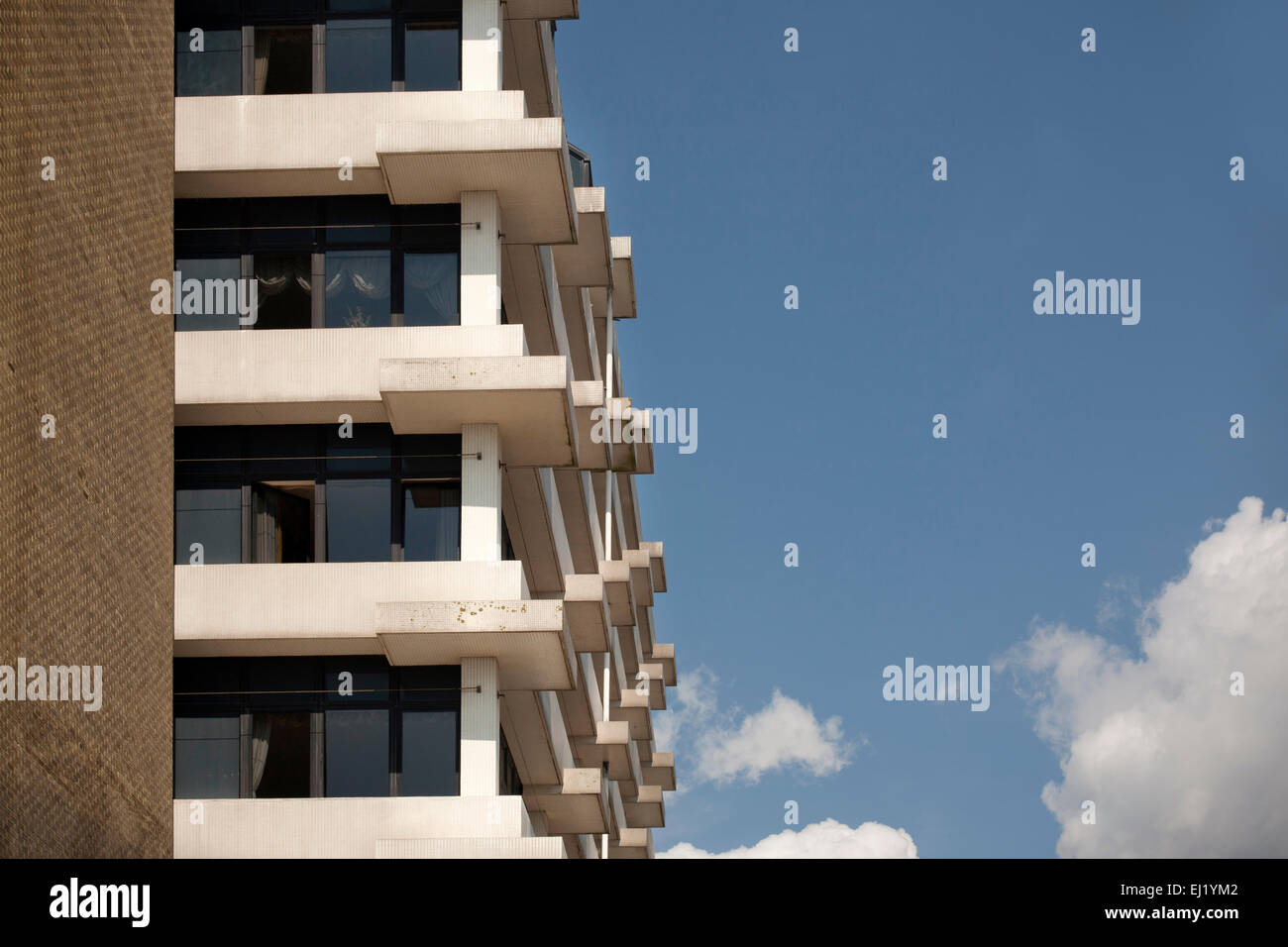 Block of flats on the seafront in Folkestone, Kent, England showing balconies against a blue sky with clouds. Stock Photo