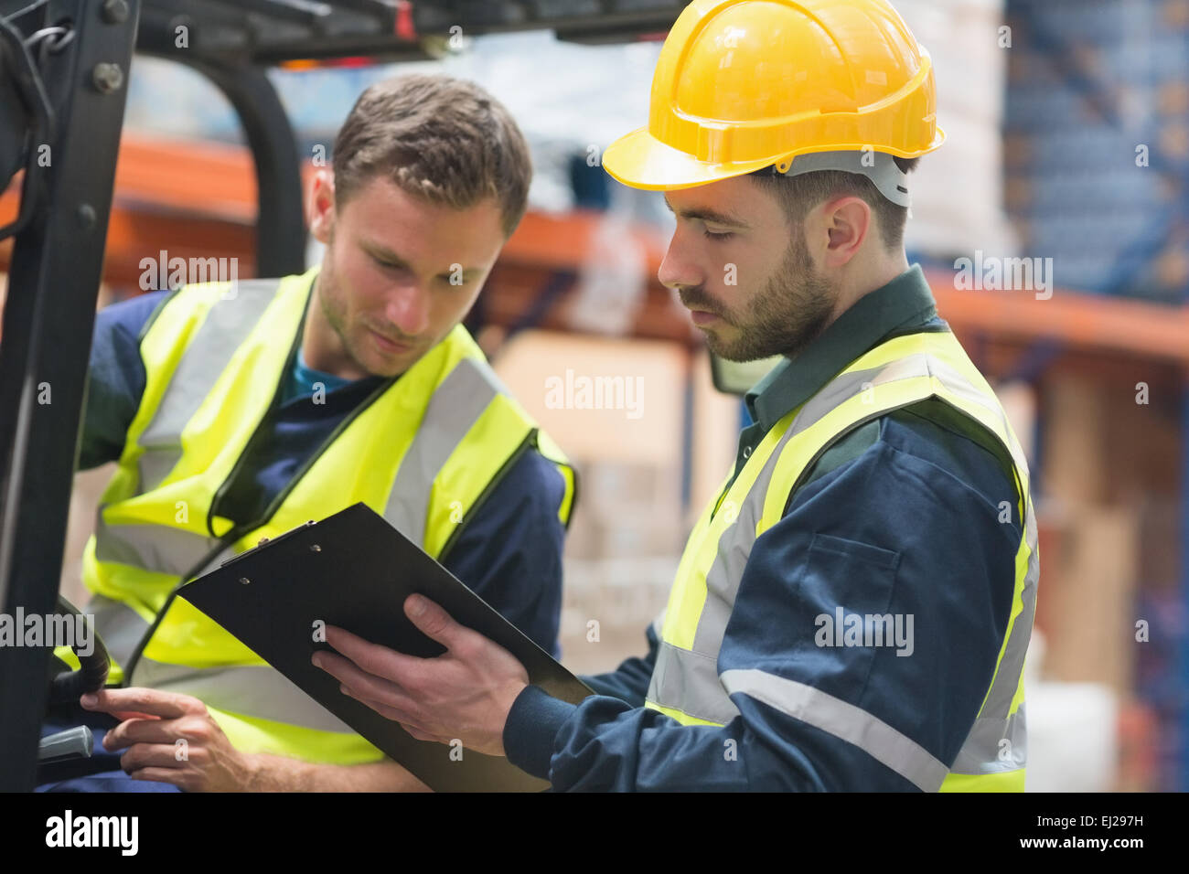 Focused warehouse workers talking together Stock Photo - Alamy