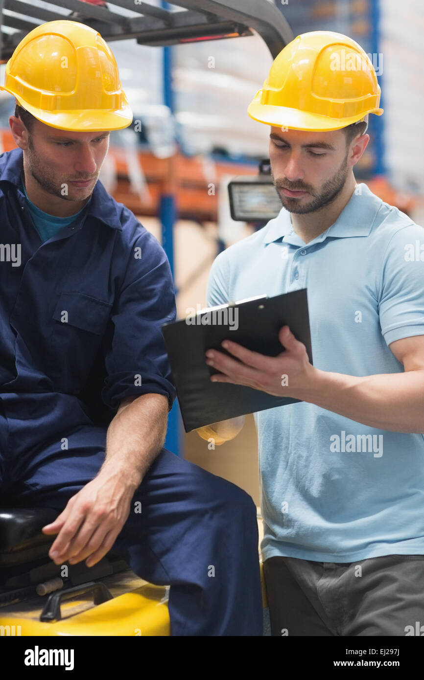 Focused warehouse workers talking together Stock Photo - Alamy
