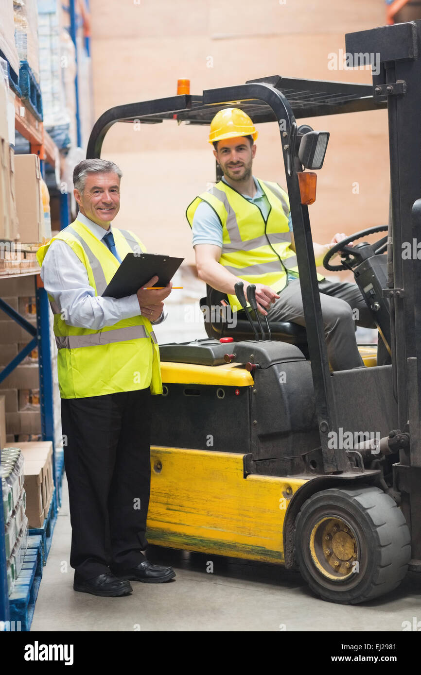 Driver operating forklift machine next to his manager Stock Photo