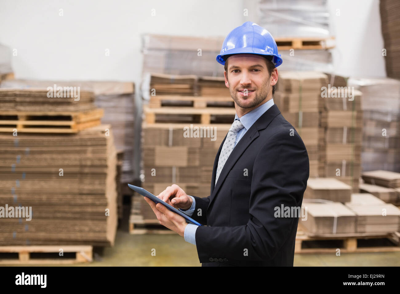 Warehouse manager wearing hard hat using tablet Stock Photo Alamy