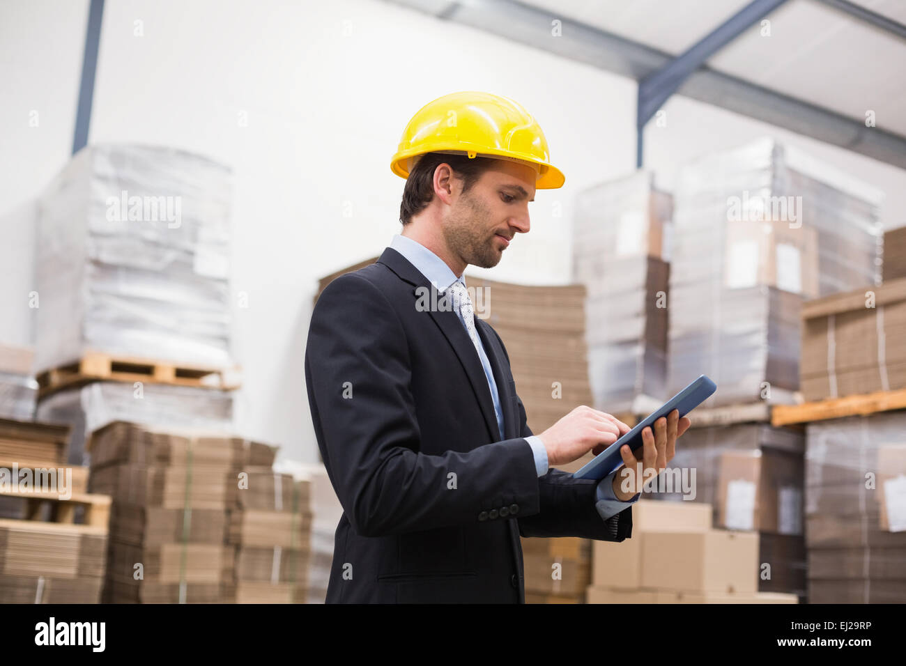Warehouse manager wearing hard hat using tablet Stock Photo Alamy