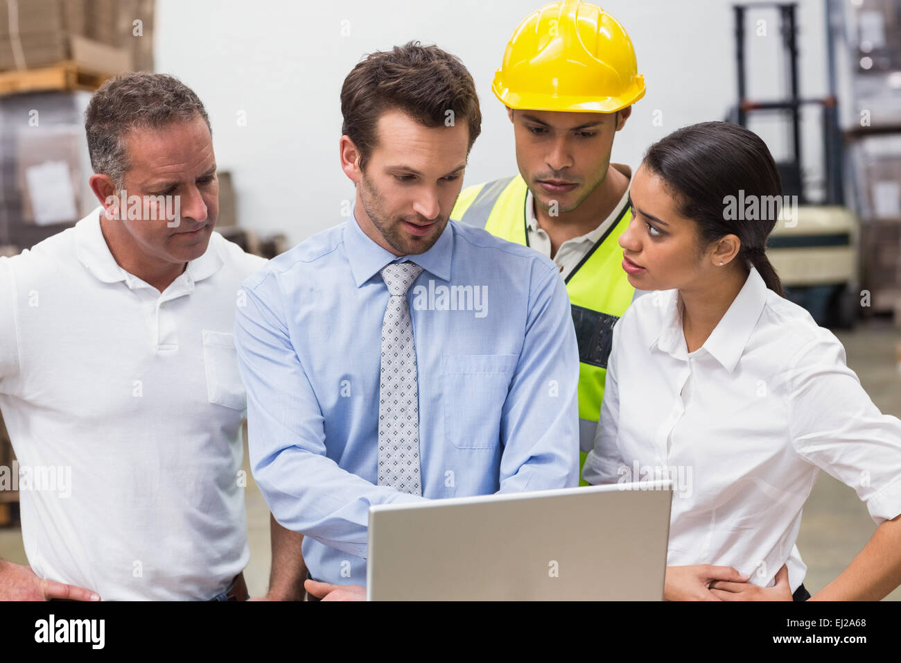 Warehouse managers and worker looking at laptop Stock Photo - Alamy