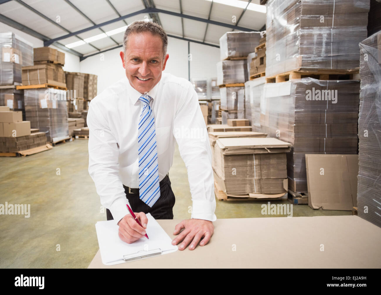 Smiling boss writing on clipboard Stock Photo - Alamy