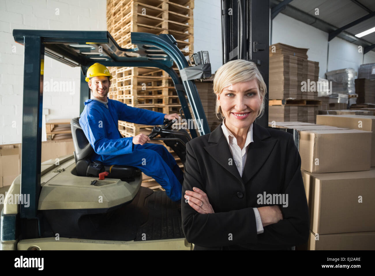 Smiling warehouse manager standing with arms crossed Stock Photo - Alamy