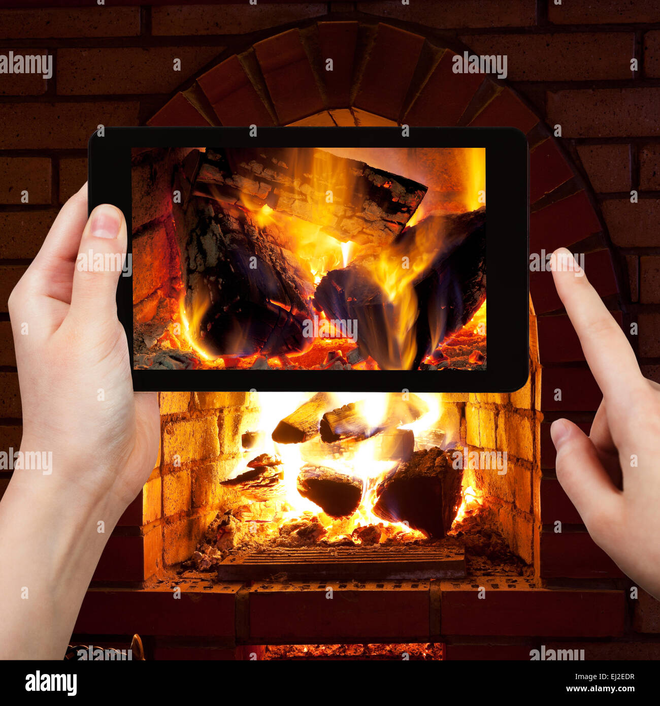 travel concept - tourist takes picture of burning wood in fireplace in evening time on smartphone, Stock Photo