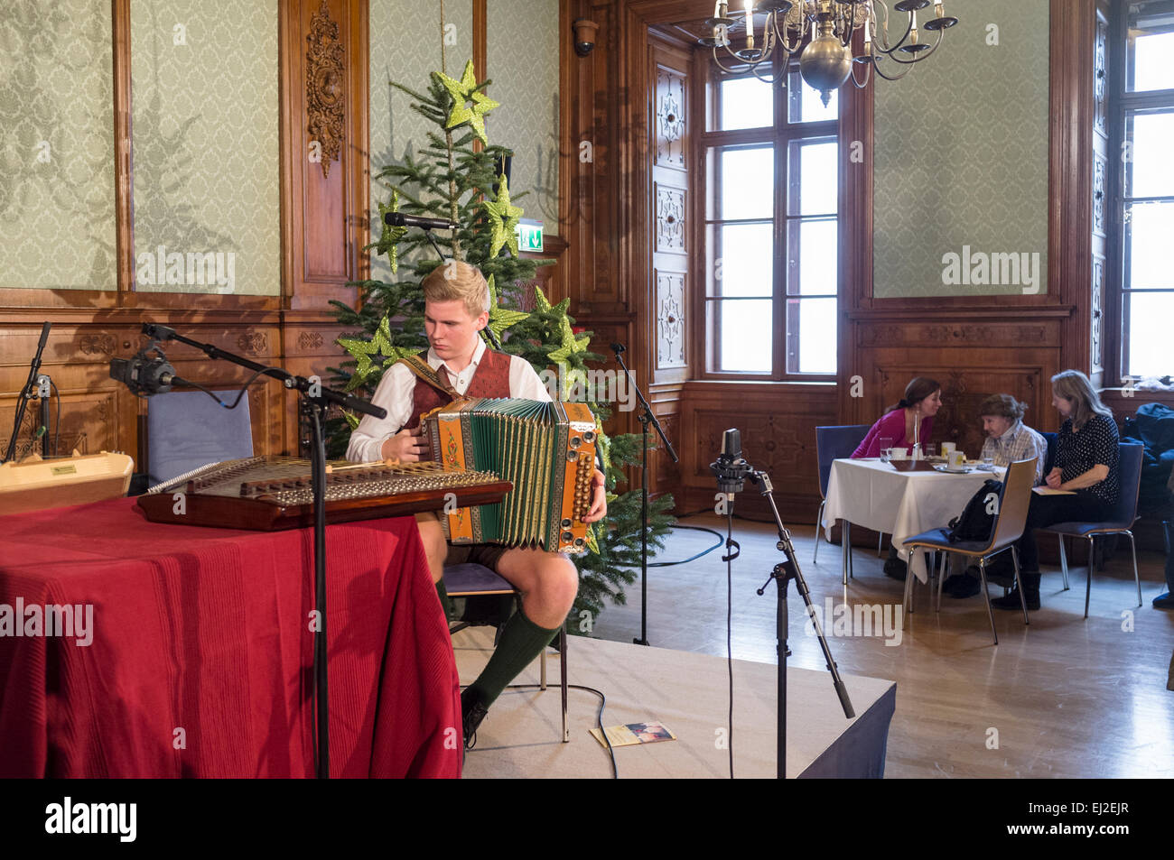 Accordionist in regional costume playing at a cafe at the Adventmarkt in Palais Niederösterreich Vienna, Austria Stock Photo