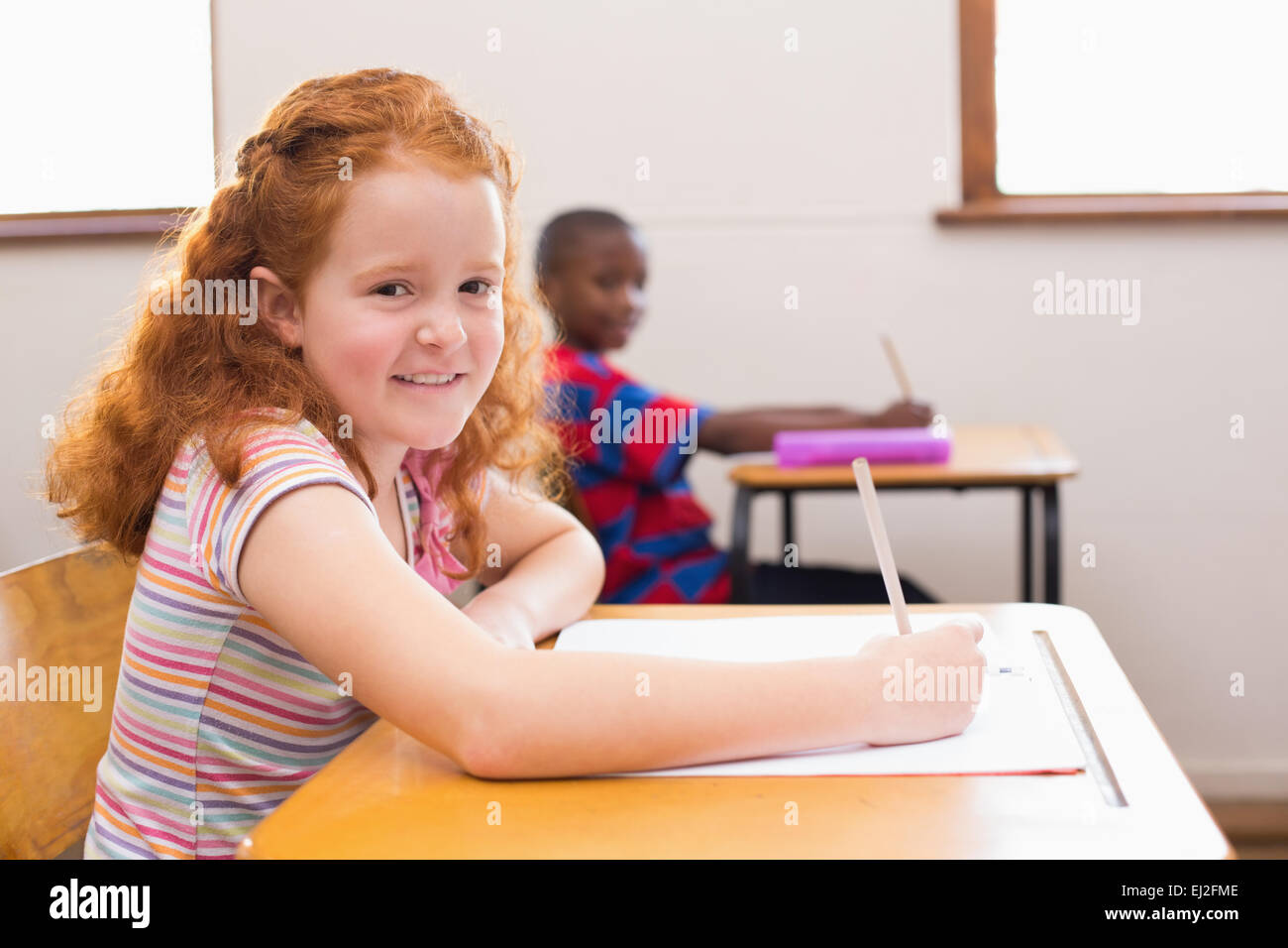 Cute pupil smiling at camera in classroom Stock Photo - Alamy