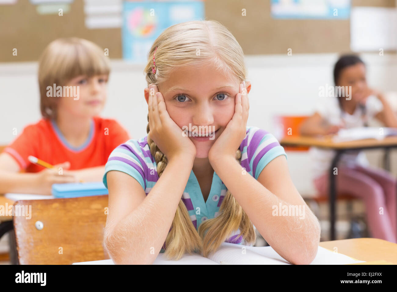 Smiling pupil sitting at her desk Stock Photo - Alamy
