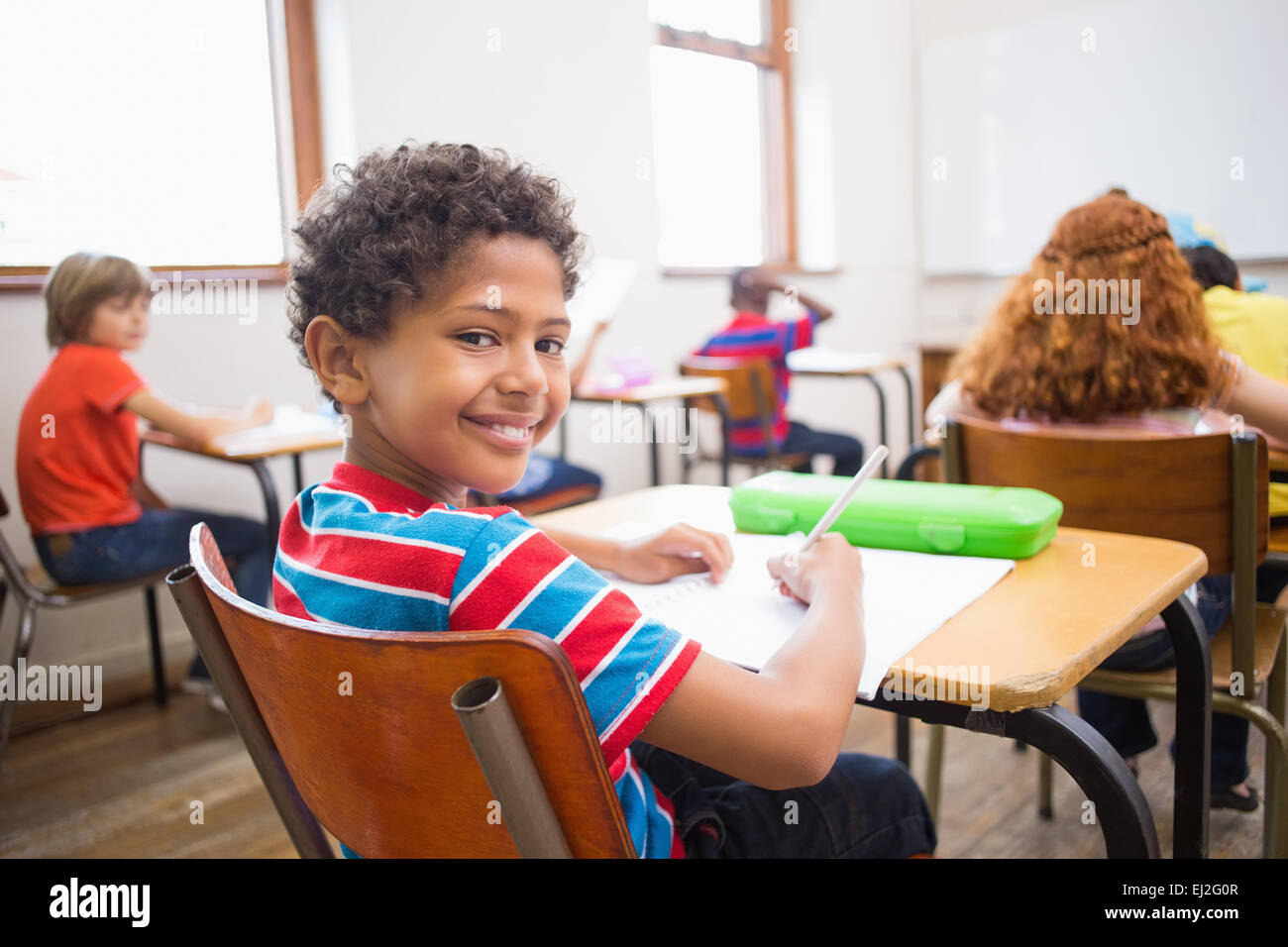 Cute pupil smiling at camera in classroom Stock Photo - Alamy