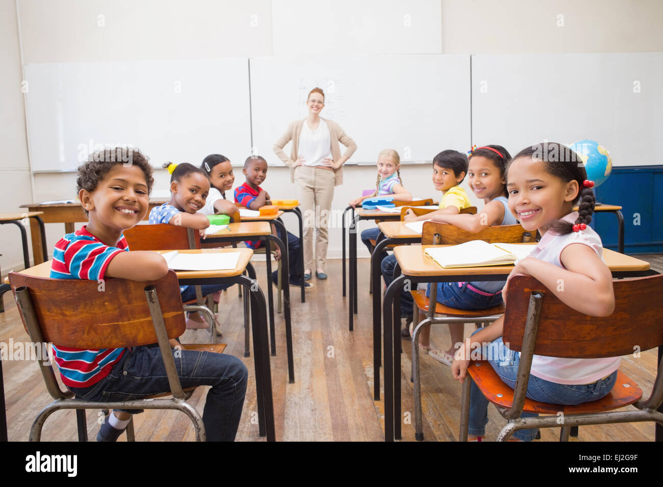 Cute pupils smiling at camera in classroom Stock Photo - Alamy