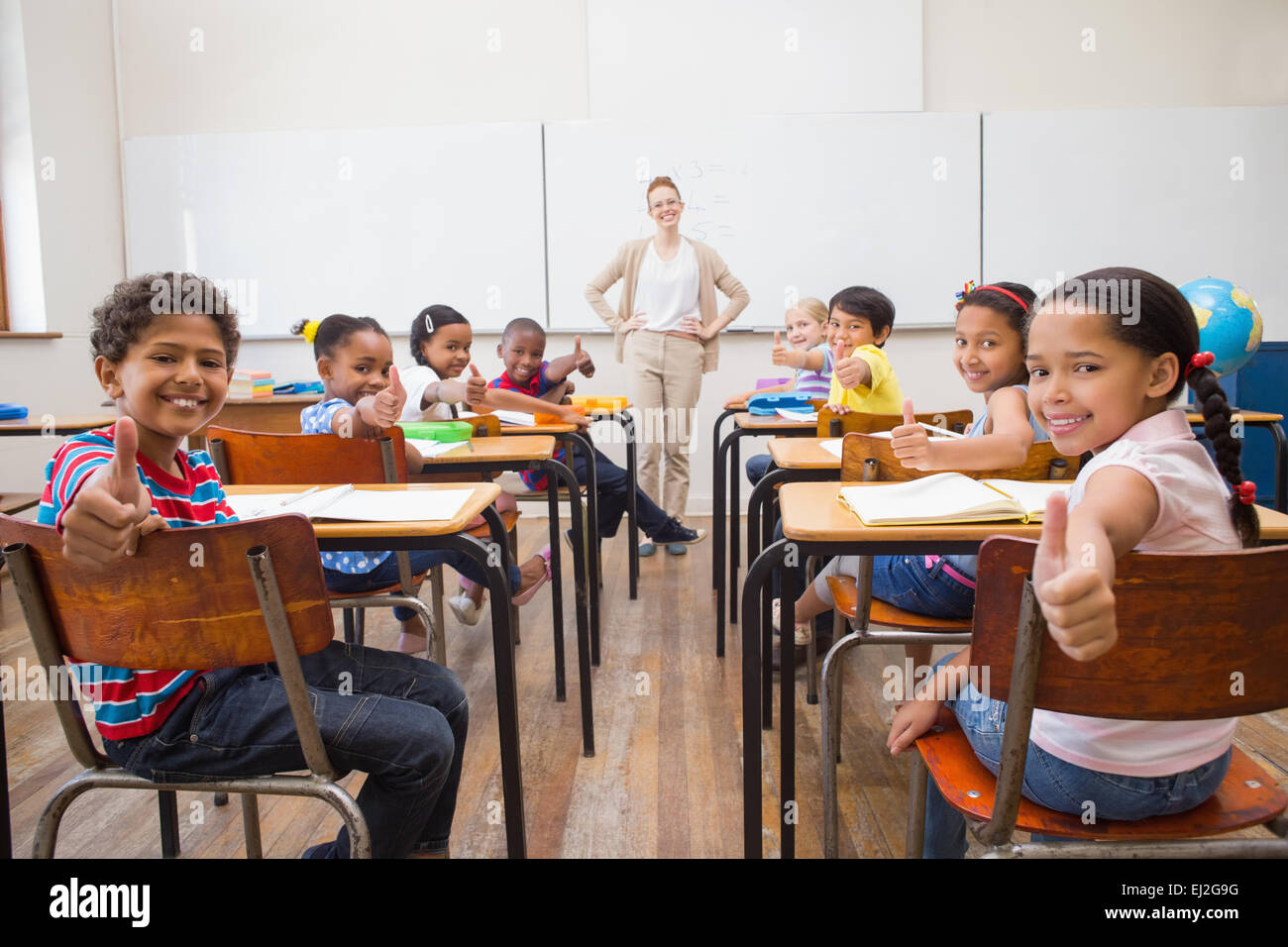 Cute pupils smiling at camera in classroom Stock Photo - Alamy