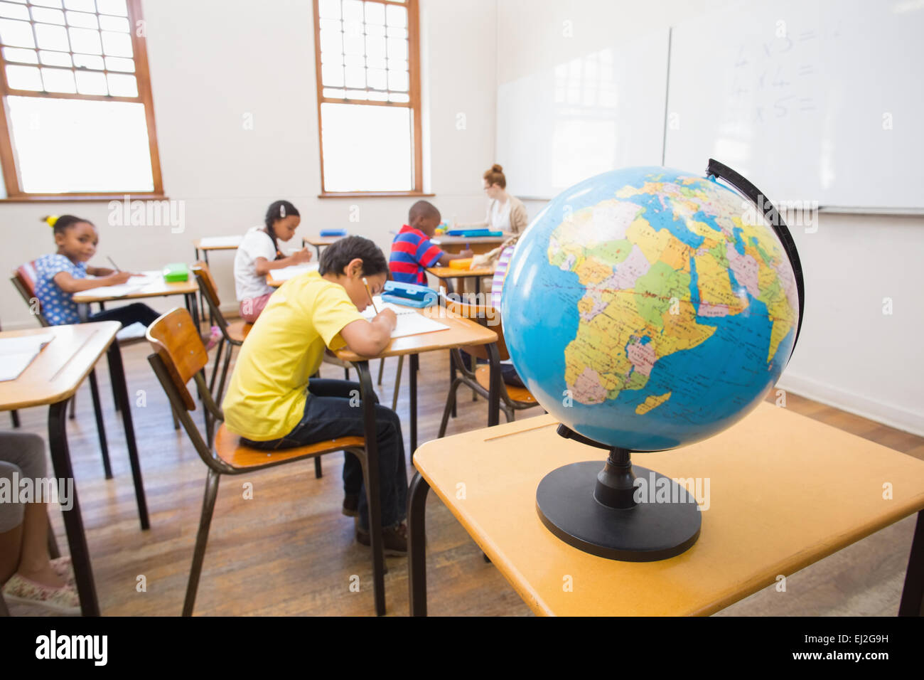 Cute pupils and teacher in classroom with globe Stock Photo - Alamy