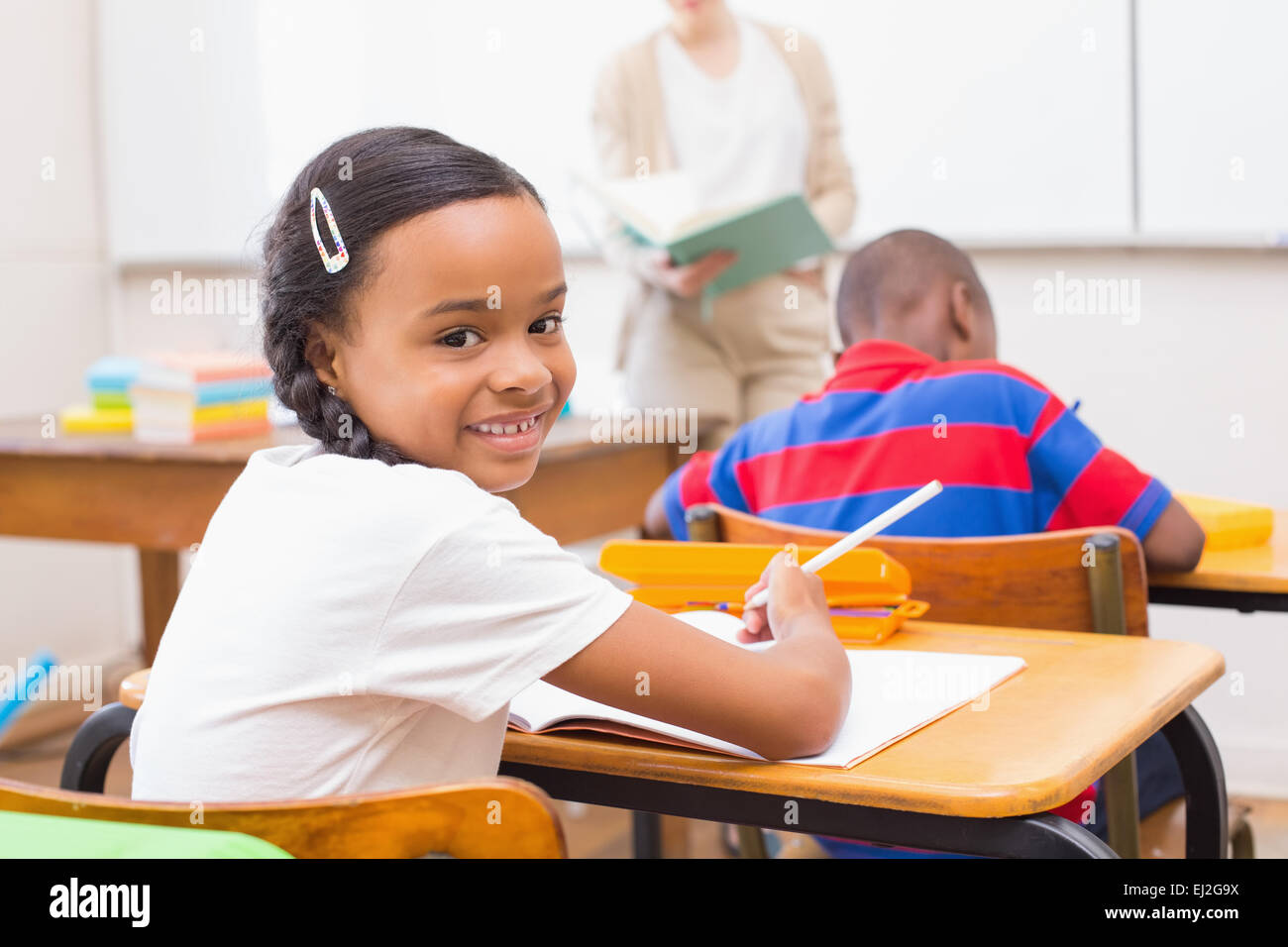 Cute pupil smiling at camera in classroom Stock Photo - Alamy