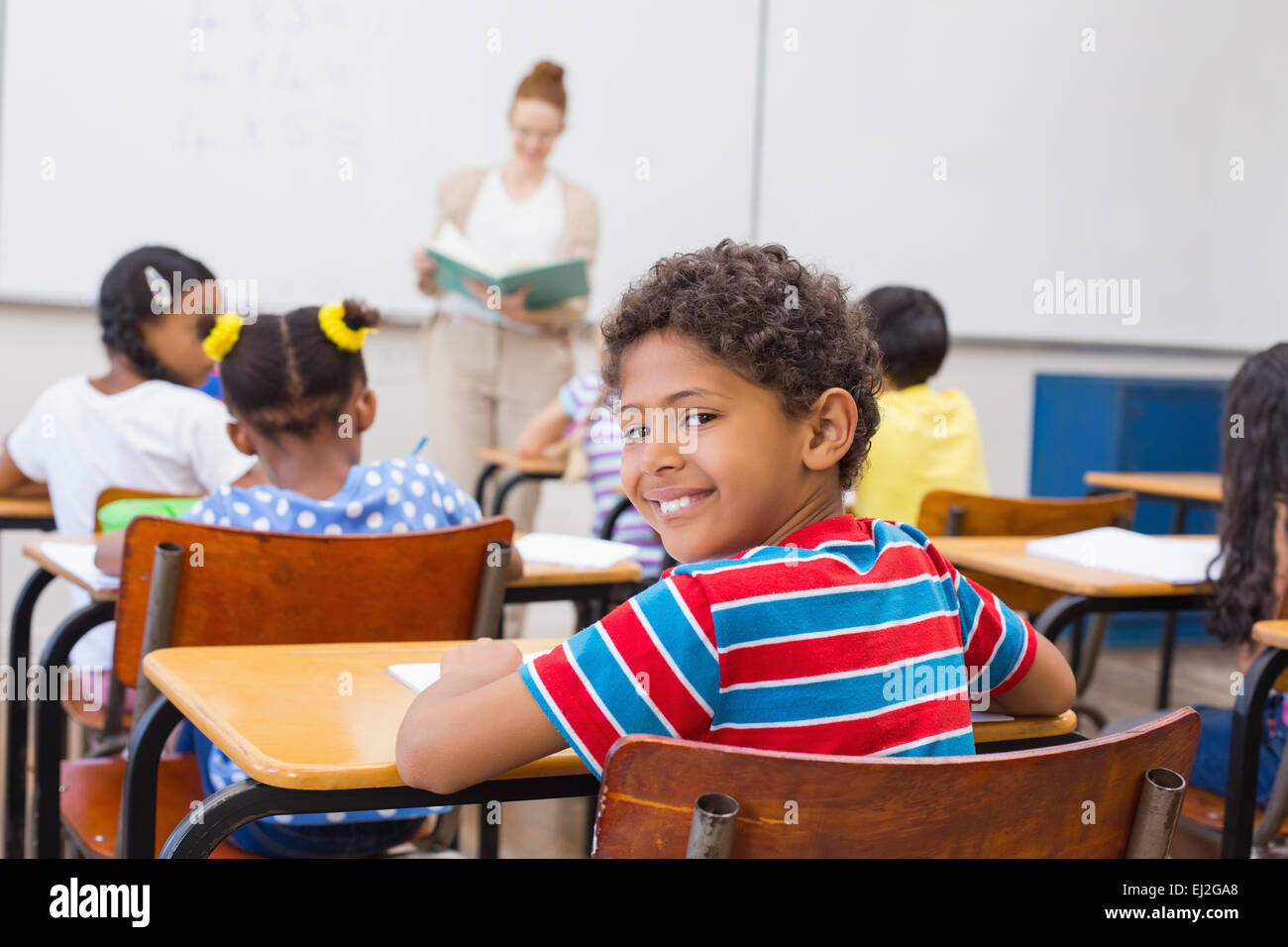 Cute pupil smiling at camera in classroom Stock Photo - Alamy