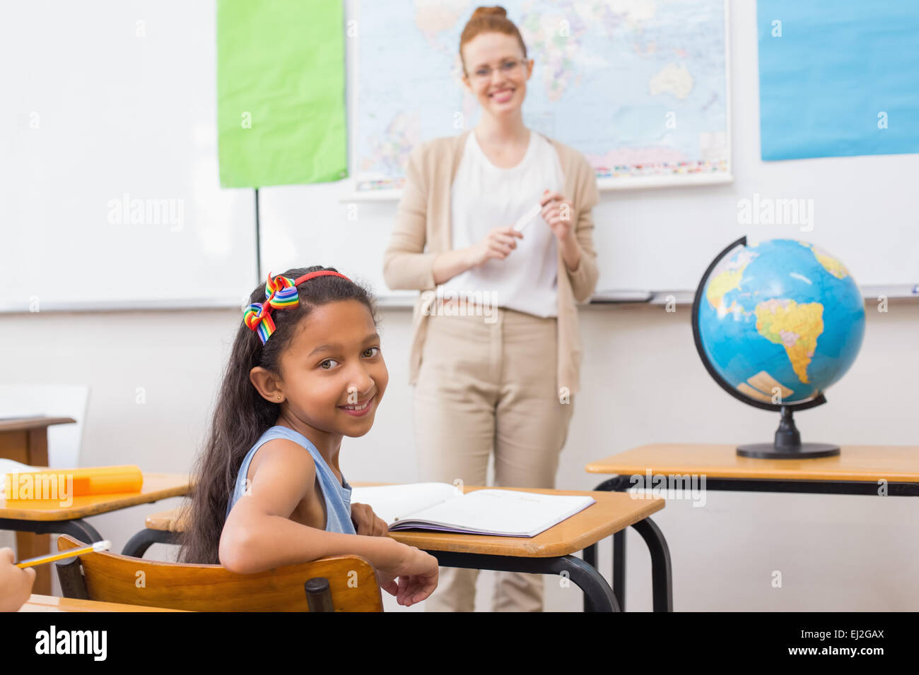 Cute pupil and teacher in classroom with globe Stock Photo - Alamy