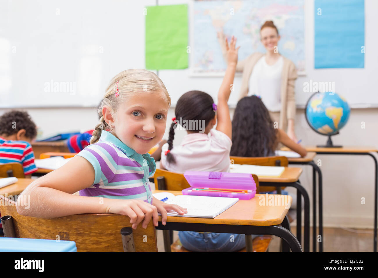 Cute pupil smiling at camera at his desk in classroom Stock Photo - Alamy