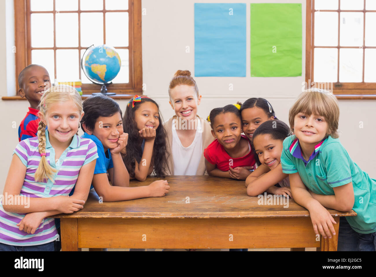 Cute pupils and teacher smiling at camera in classroom Stock Photo - Alamy