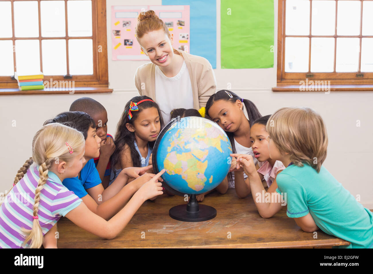 Cute pupils and teacher in classroom with globe Stock Photo - Alamy