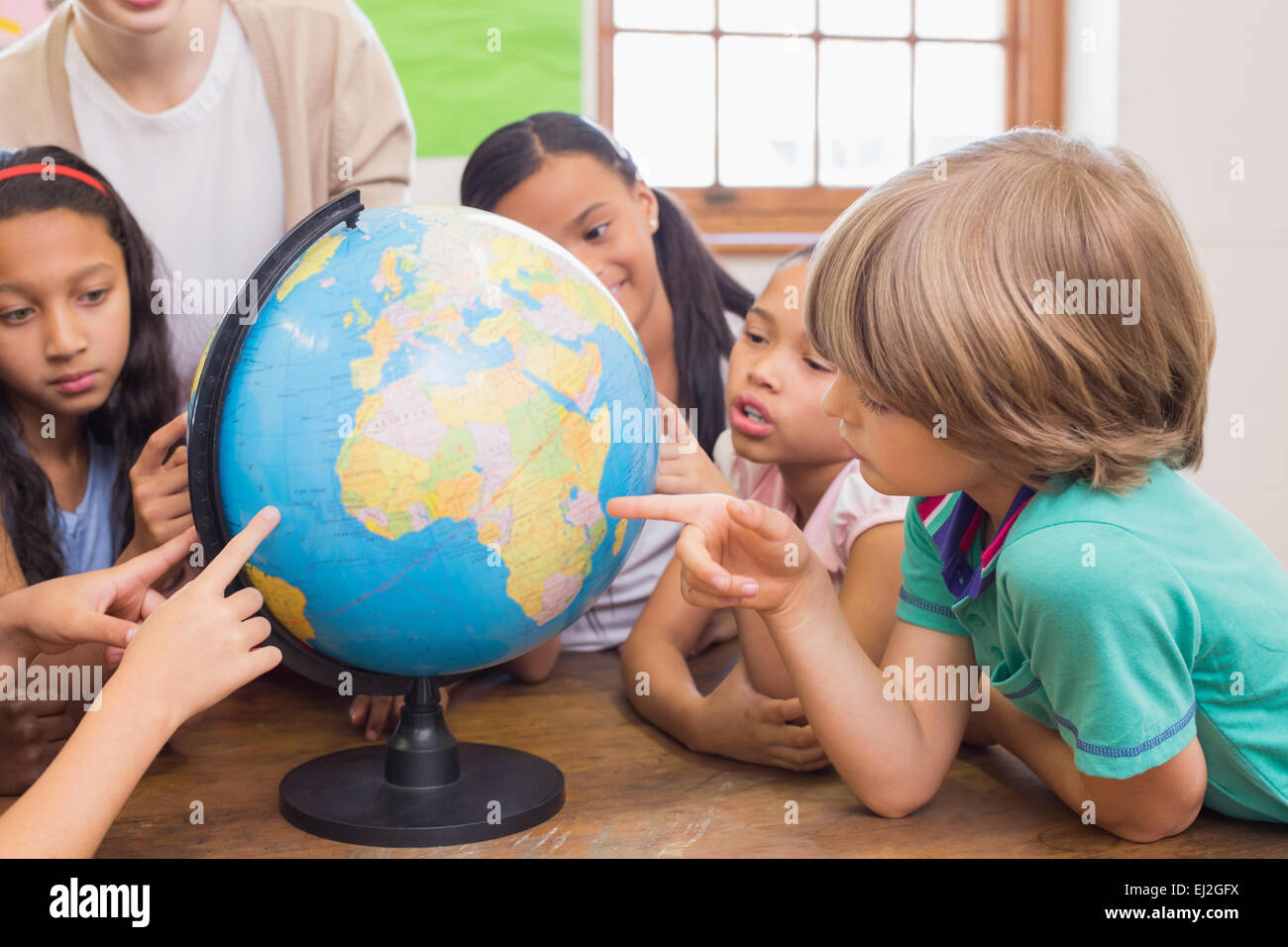 Cute pupils and teacher in classroom with globe Stock Photo - Alamy