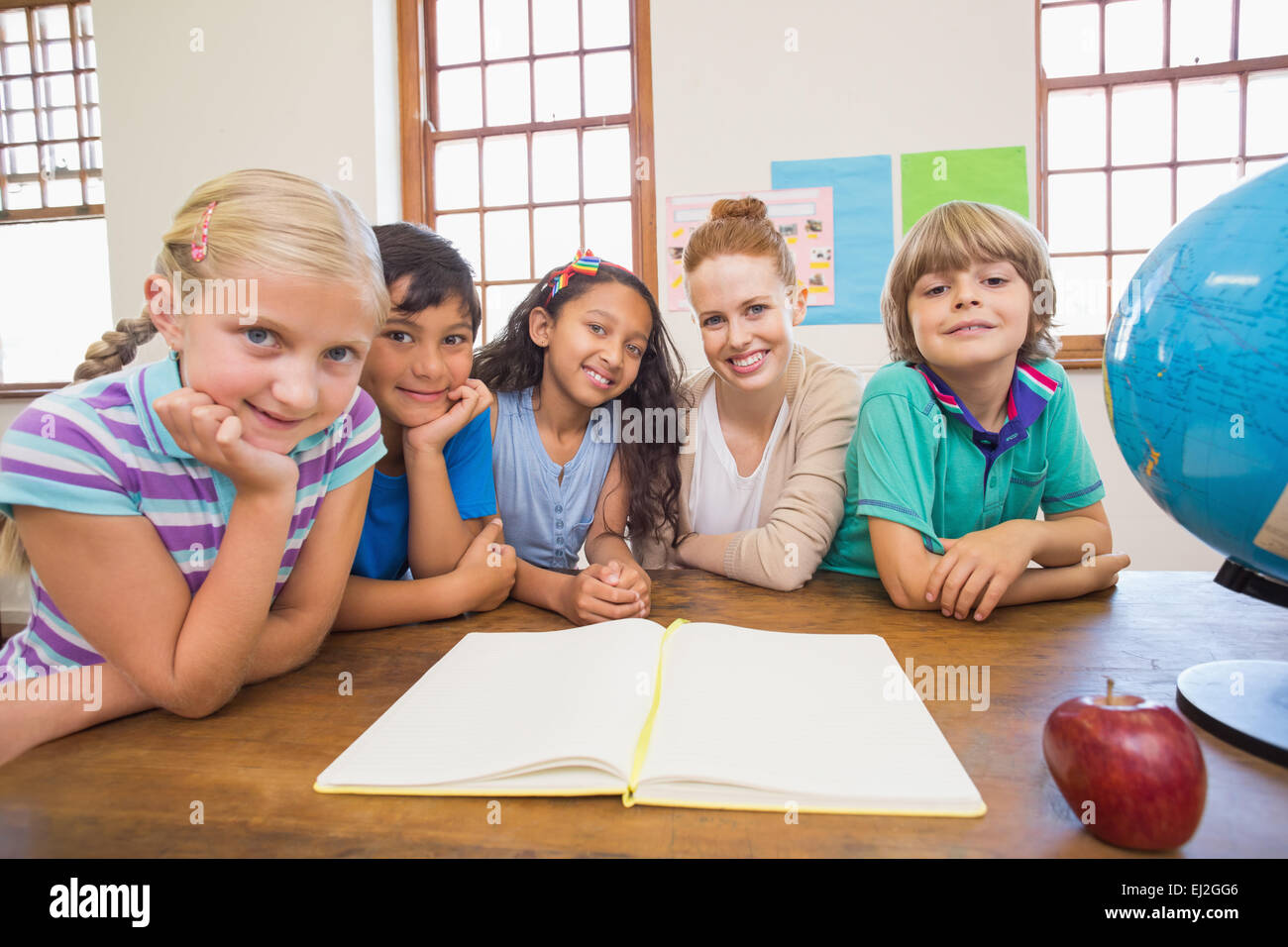 Cute pupils and teacher smiling at camera in classroom Stock Photo - Alamy