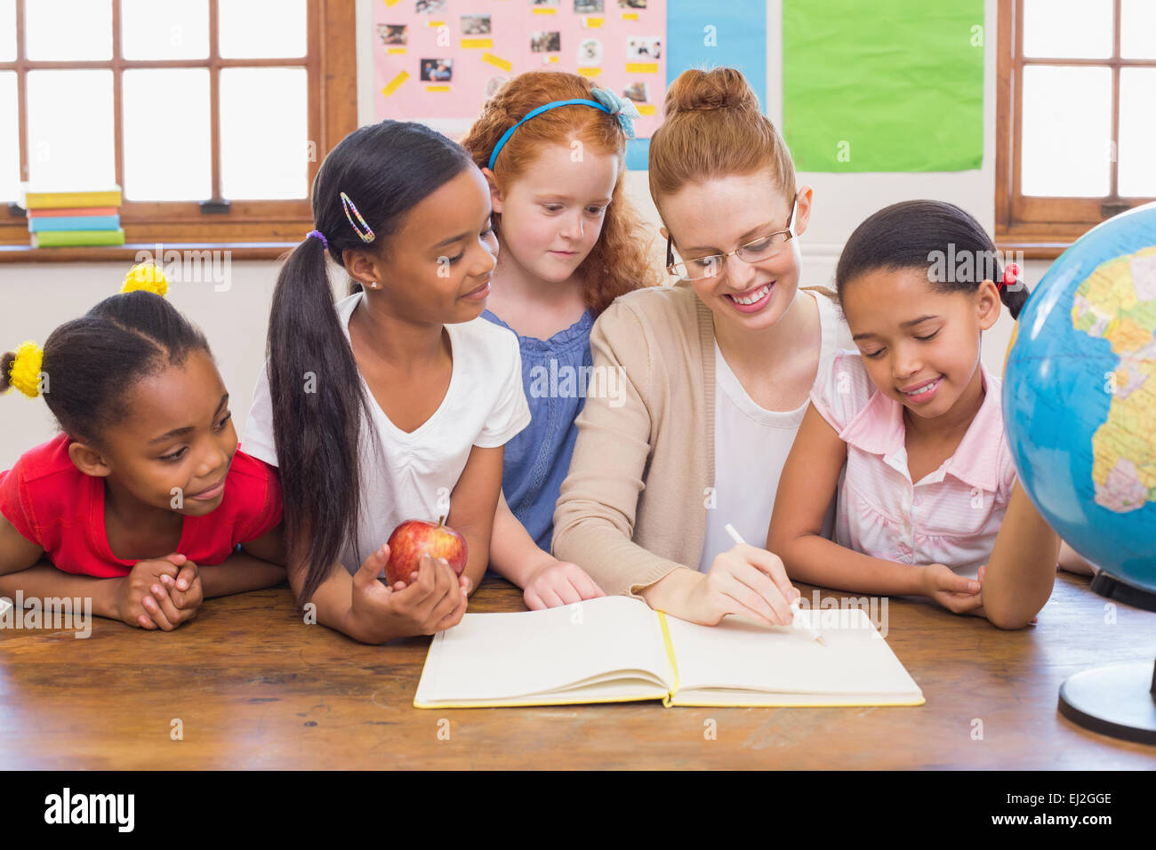 Cute pupils and teacher smiling at camera in classroom Stock Photo - Alamy