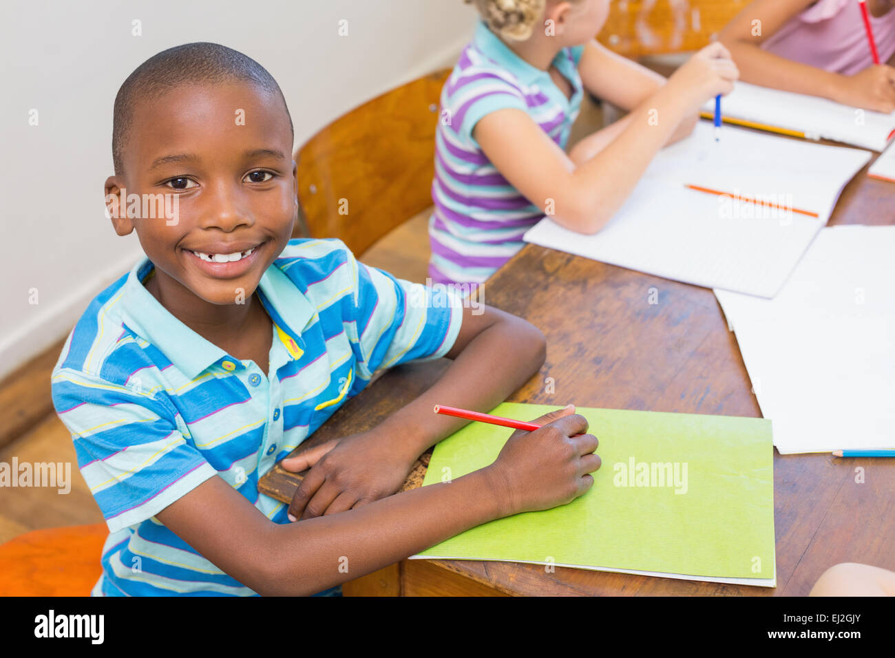Cute pupil smiling at camera in classroom Stock Photo - Alamy