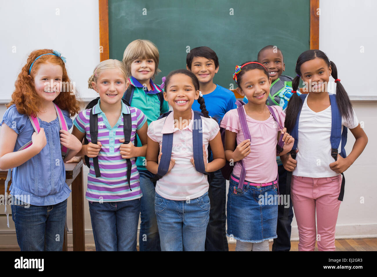 Cute pupils smiling at camera in classroom Stock Photo - Alamy
