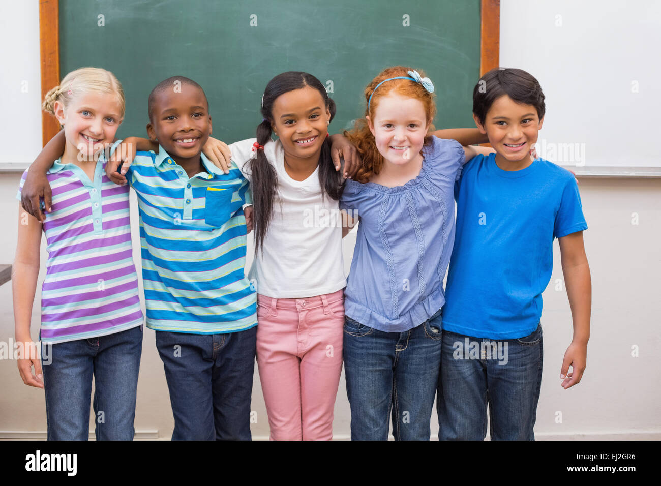 Cute pupils smiling at camera in classroom Stock Photo - Alamy