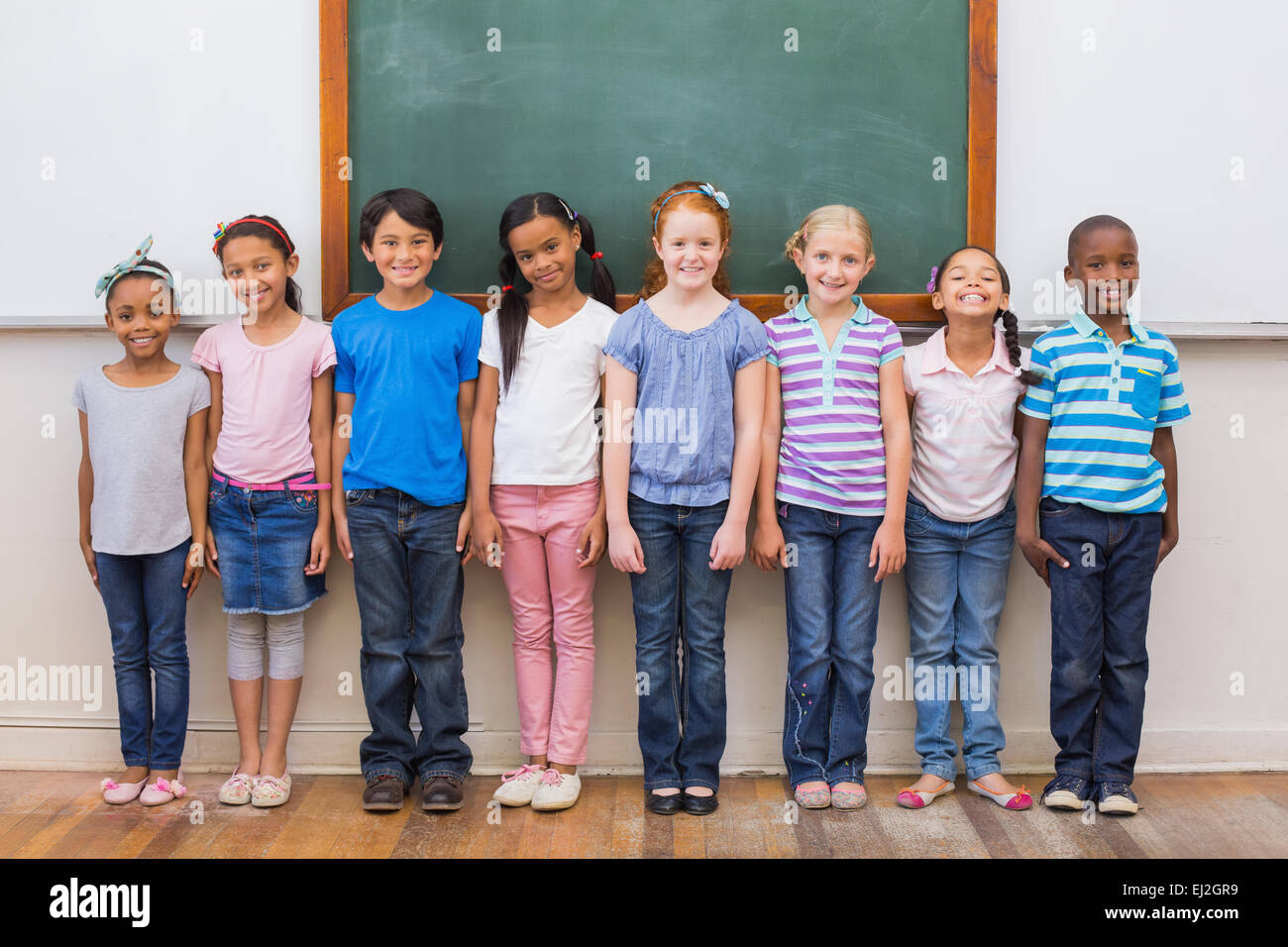 Cute pupils smiling at camera in classroom Stock Photo - Alamy