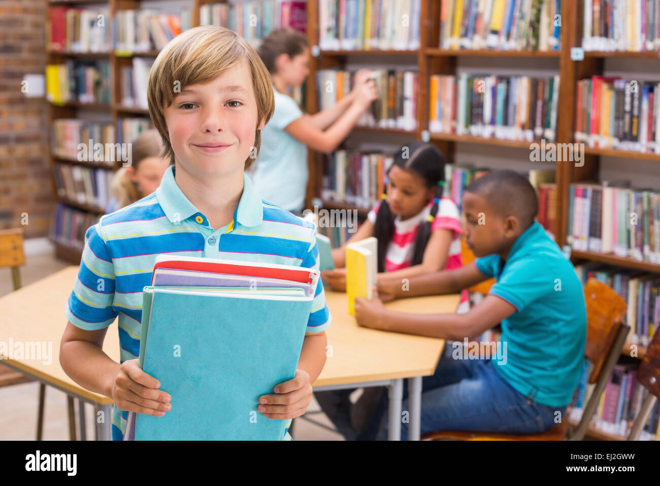 Cute pupil smiling at camera in library Stock Photo - Alamy