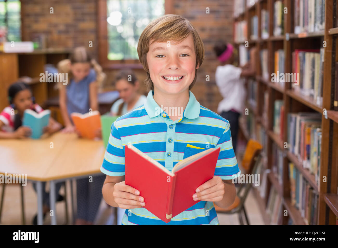 Cute pupil smiling at camera in library Stock Photo - Alamy