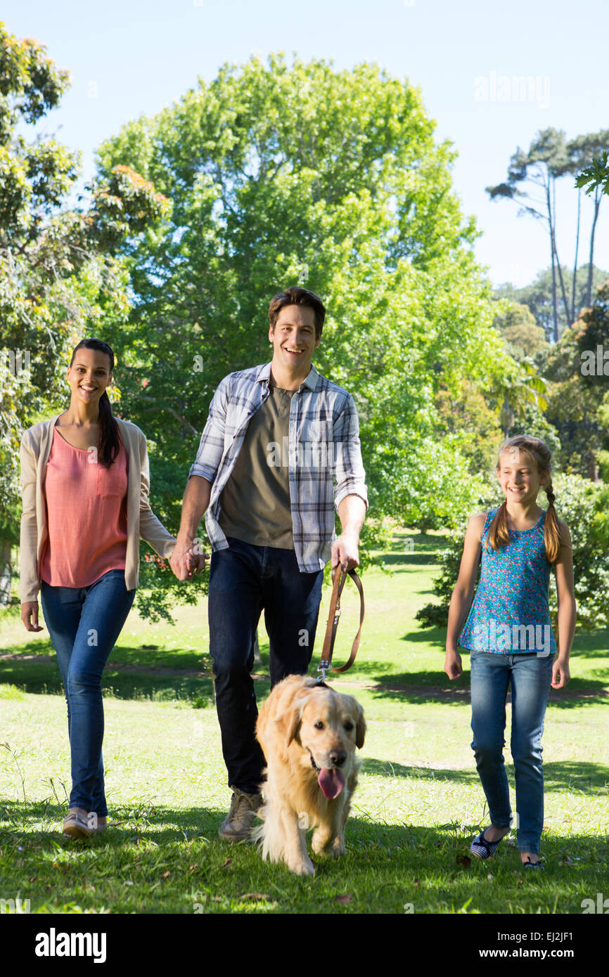 Happy family walking their dog in the park Stock Photo