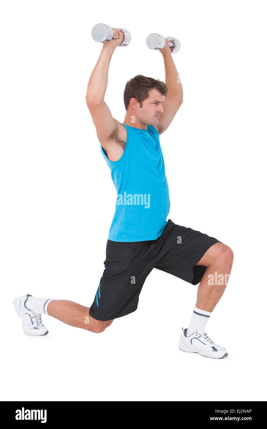 Fit man lifting dumbbells while lunging Stock Photo