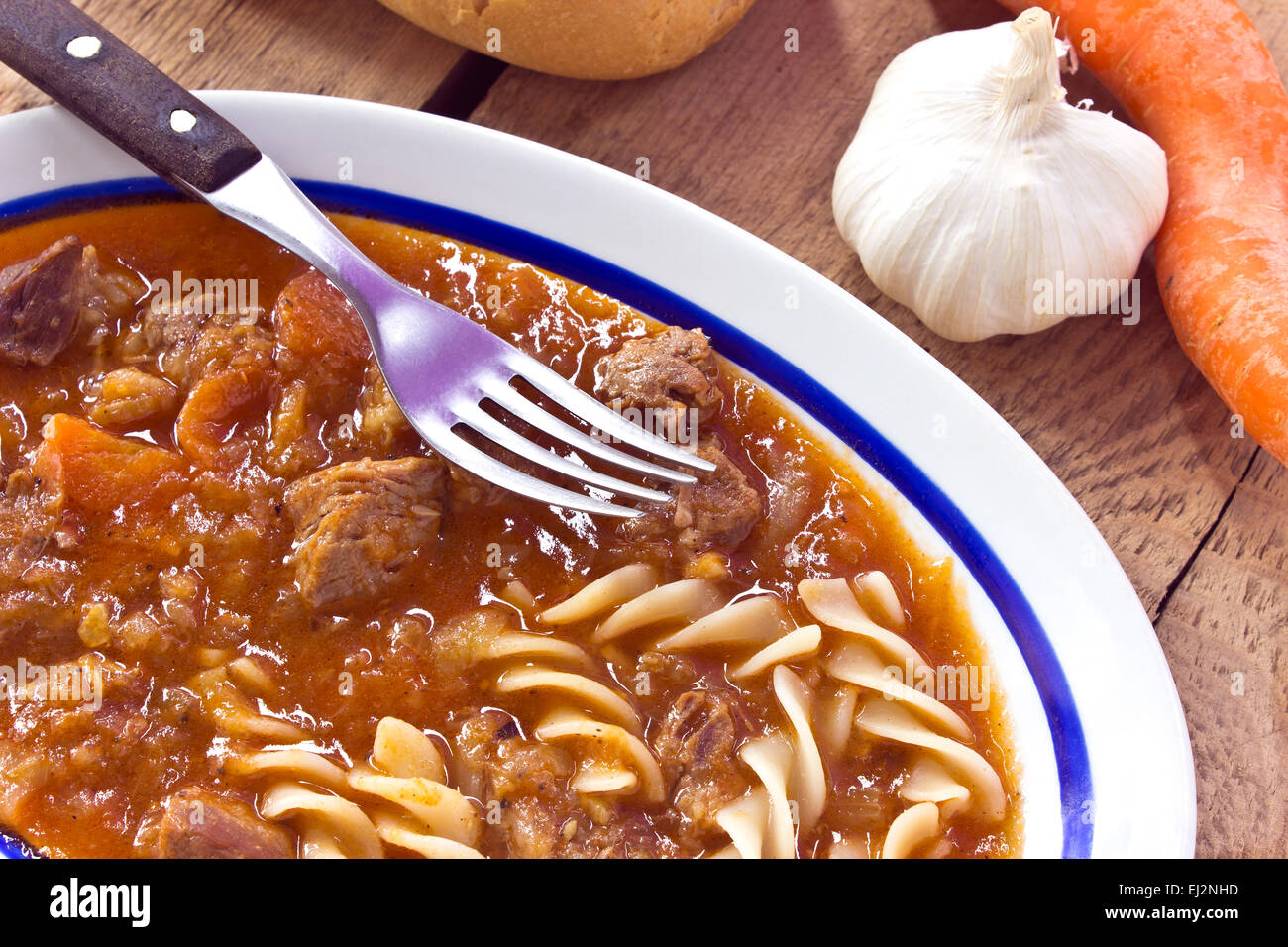 Beef stew with pasta on wooden background Stock Photo