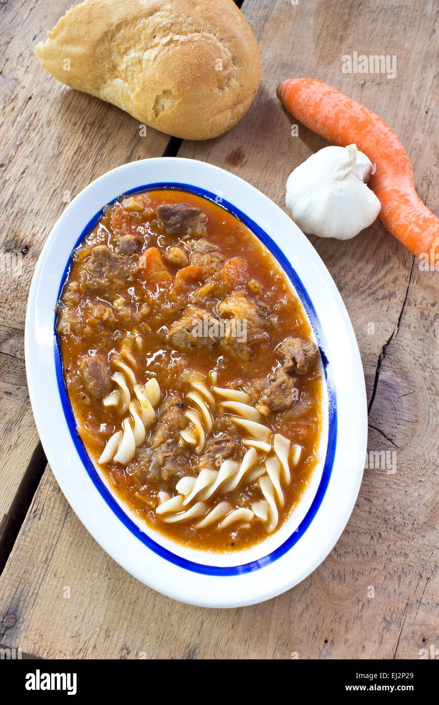 Beef goulash with pasta on wooden background Stock Photo