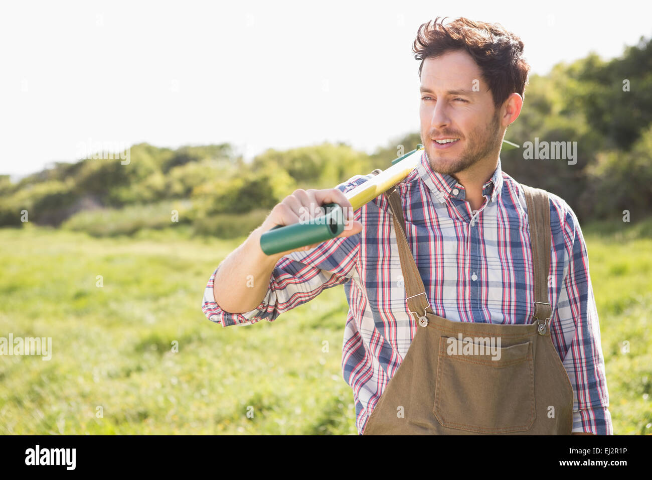 Happy farmer carrying his shovel Stock Photo - Alamy