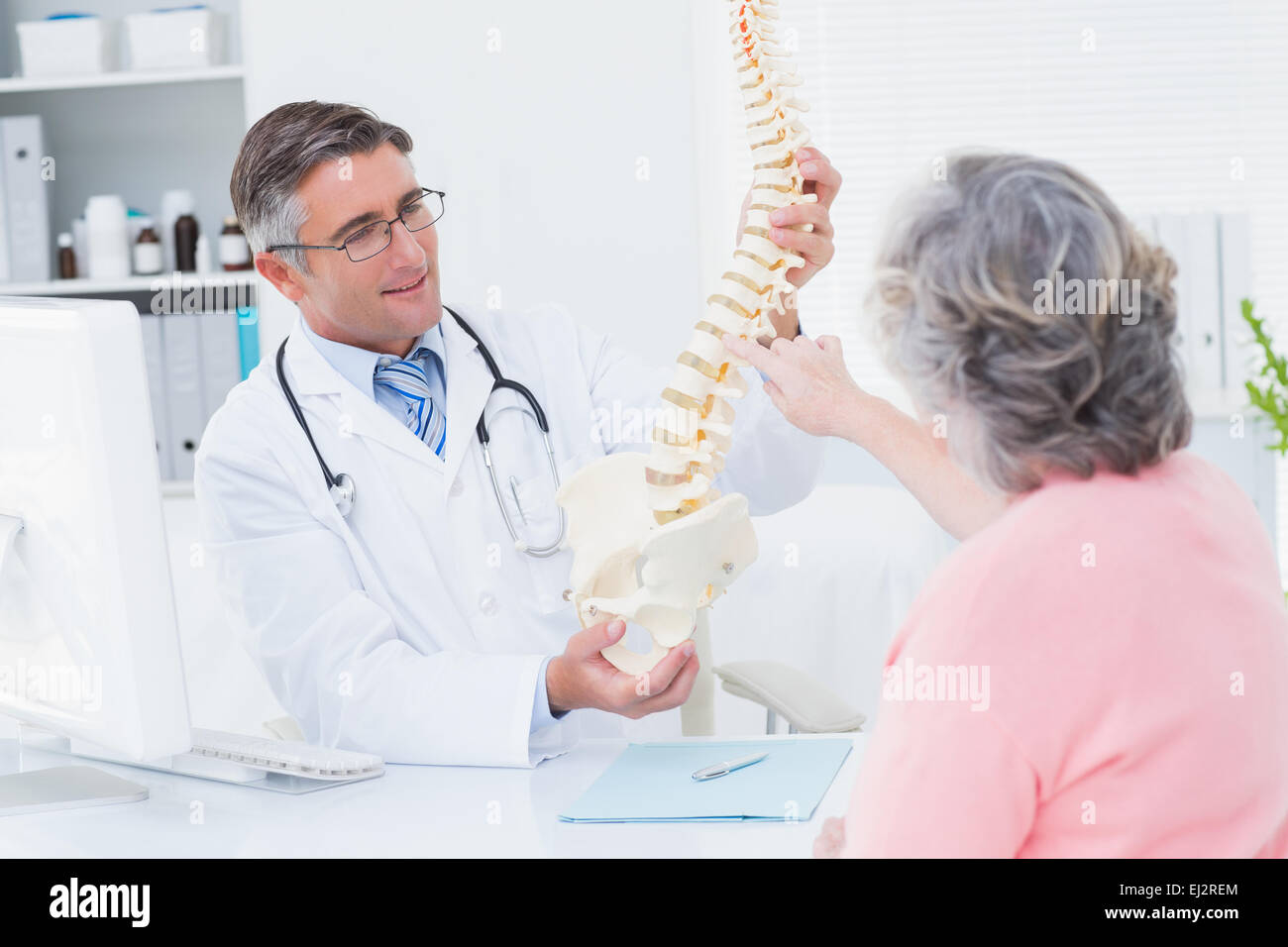 Doctor showing anatomical spine while patient touching it Stock Photo