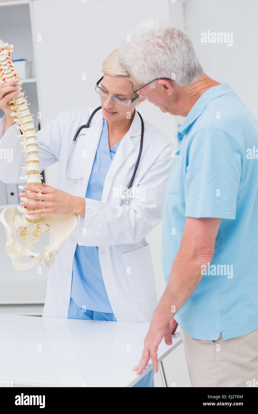 Orthopedic doctor and senior patient discussing over anatomical spine Stock Photo