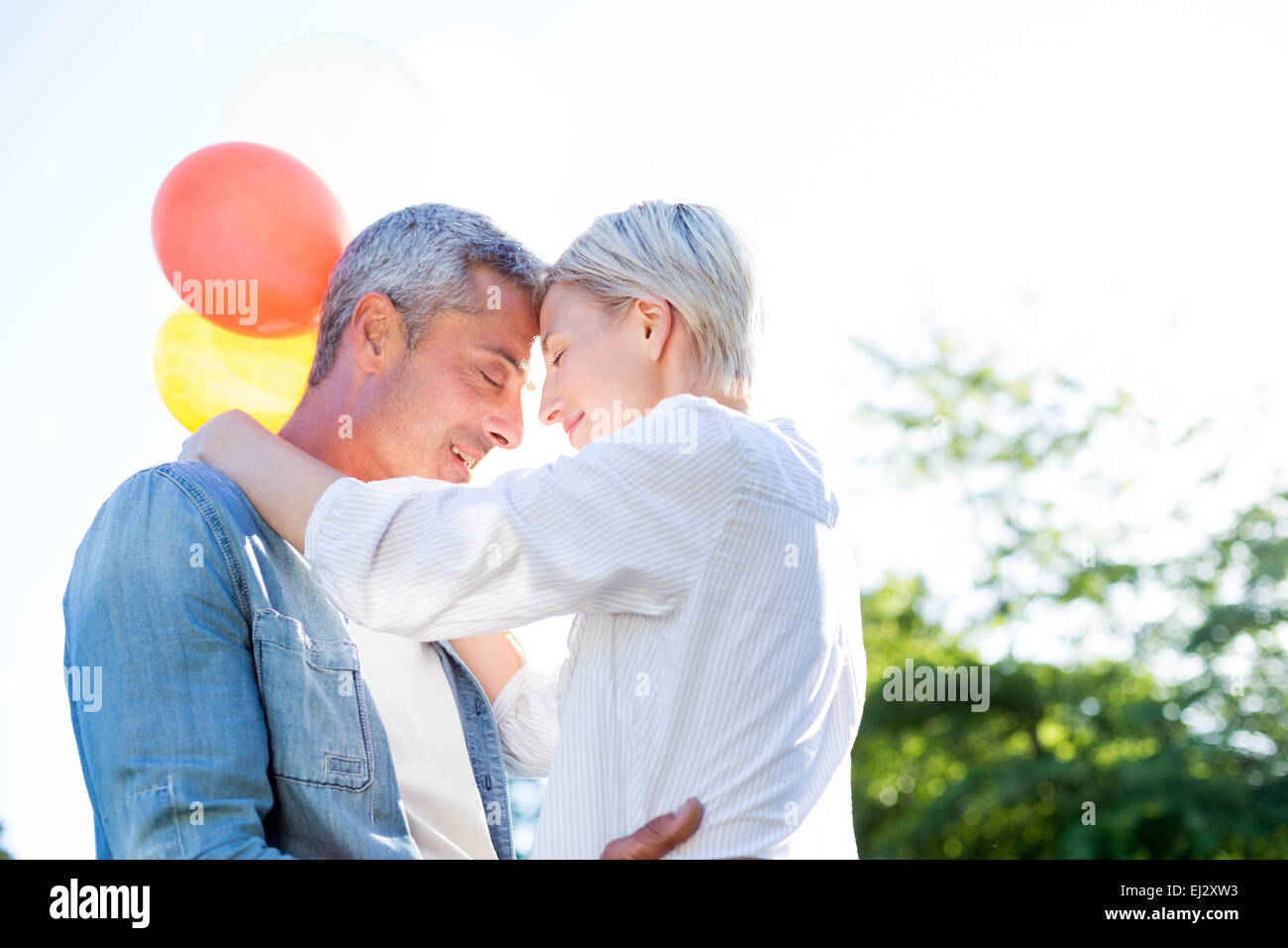 Cute couple hugging and holding balloons at the park Stock Photo - Alamy