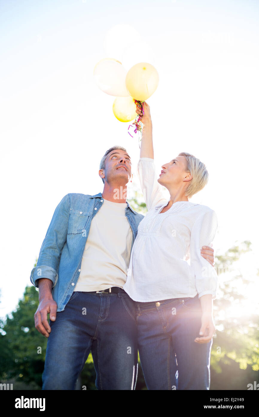 Cute couple holding up balloons at the park Stock Photo - Alamy