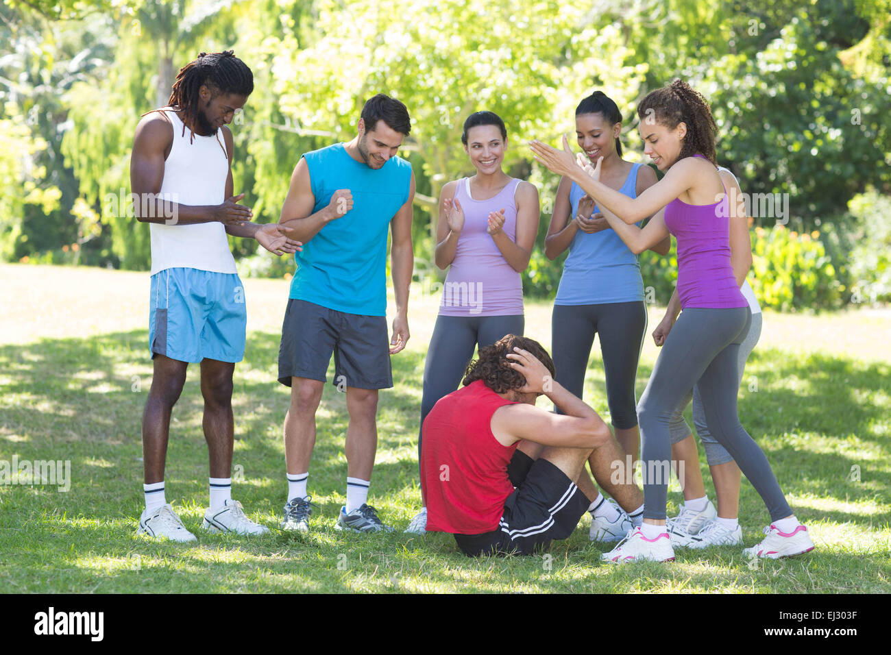 Fitness group encouraging man doing sit ups Stock Photo
