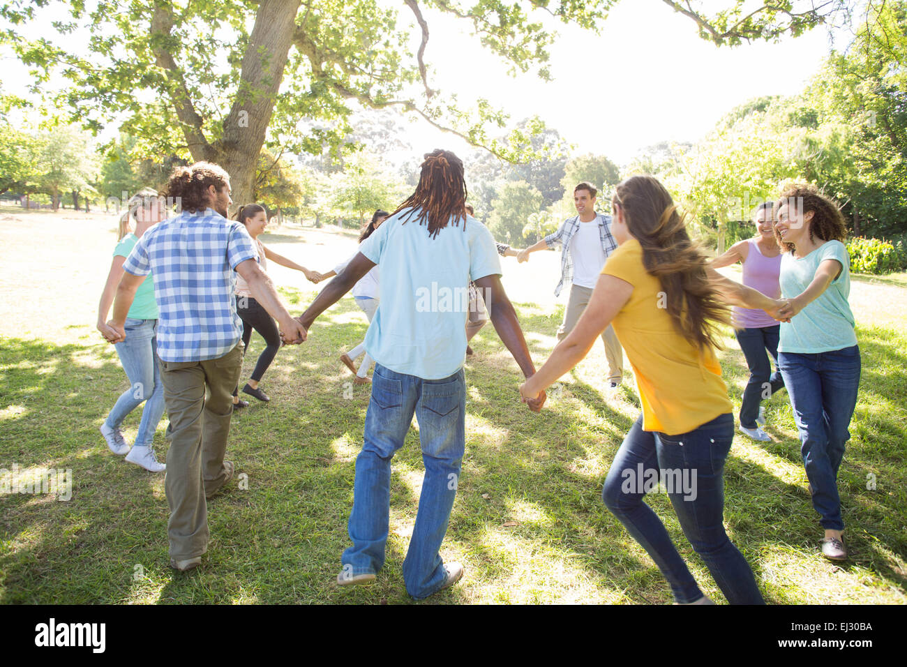 Happy friends in the park holding hands Stock Photo - Alamy