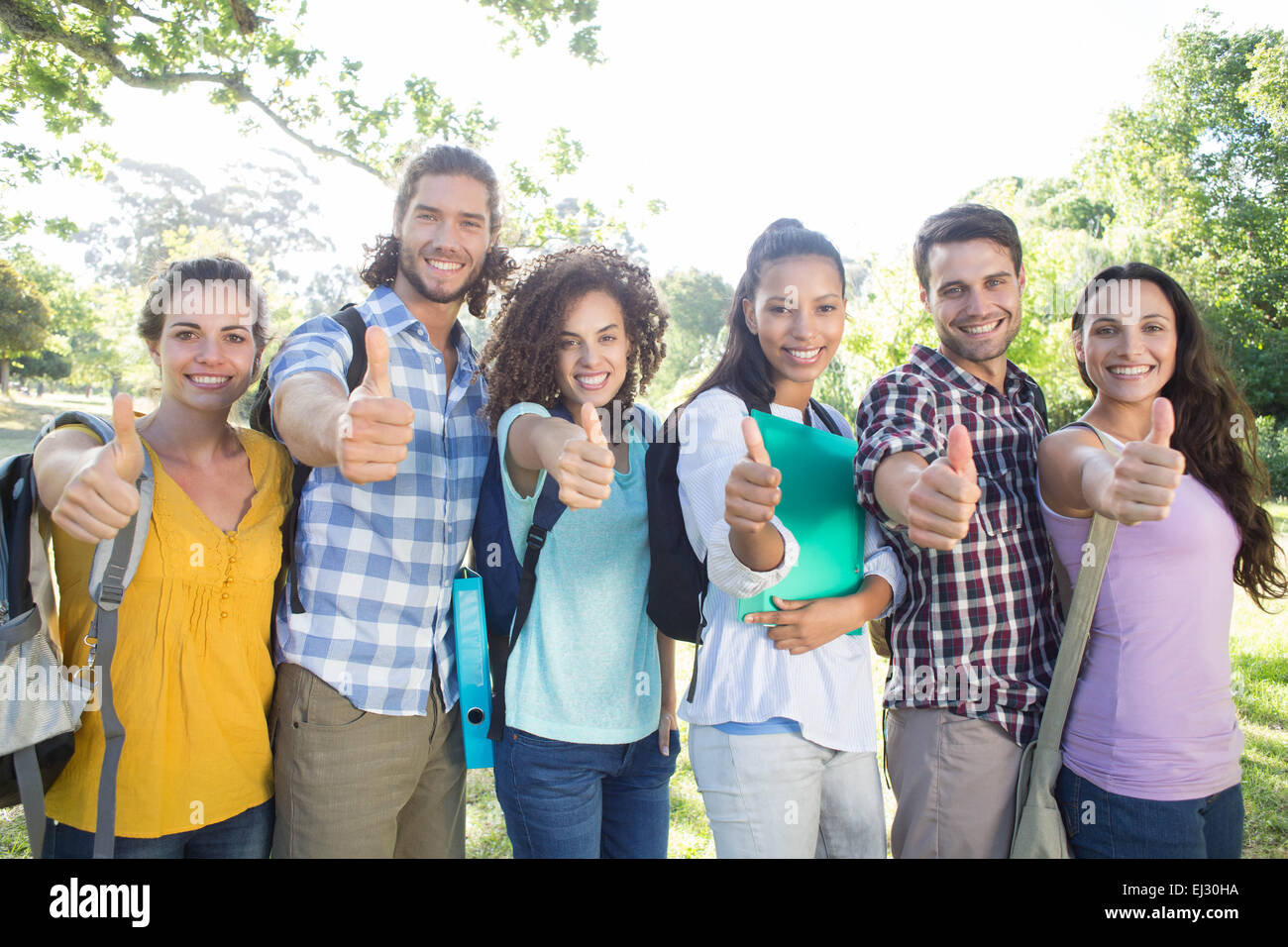 Smiling students showing thumbs up Stock Photo - Alamy