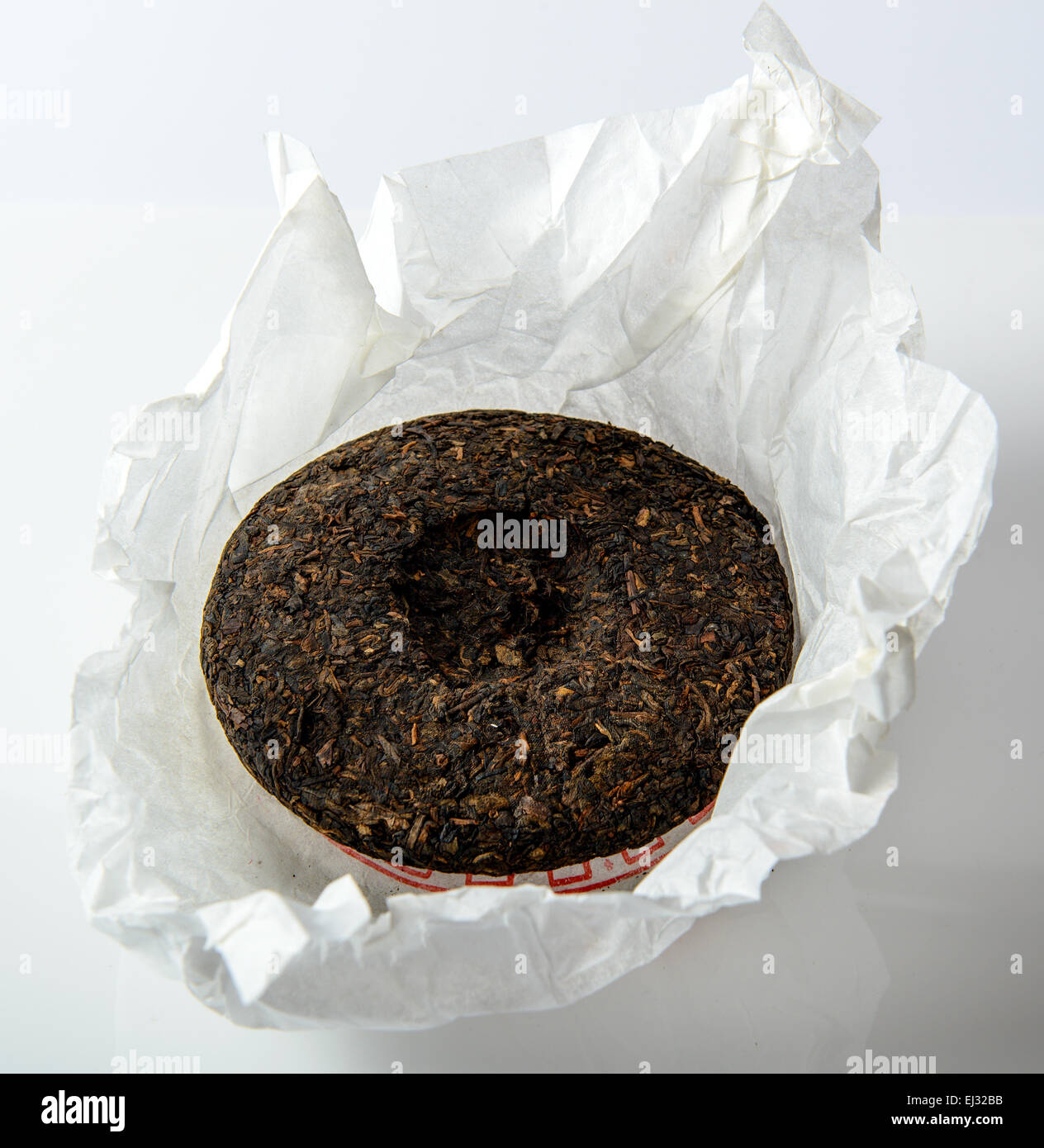 Disc of chinese puer tea in unwrapped packing on green background Stock ...