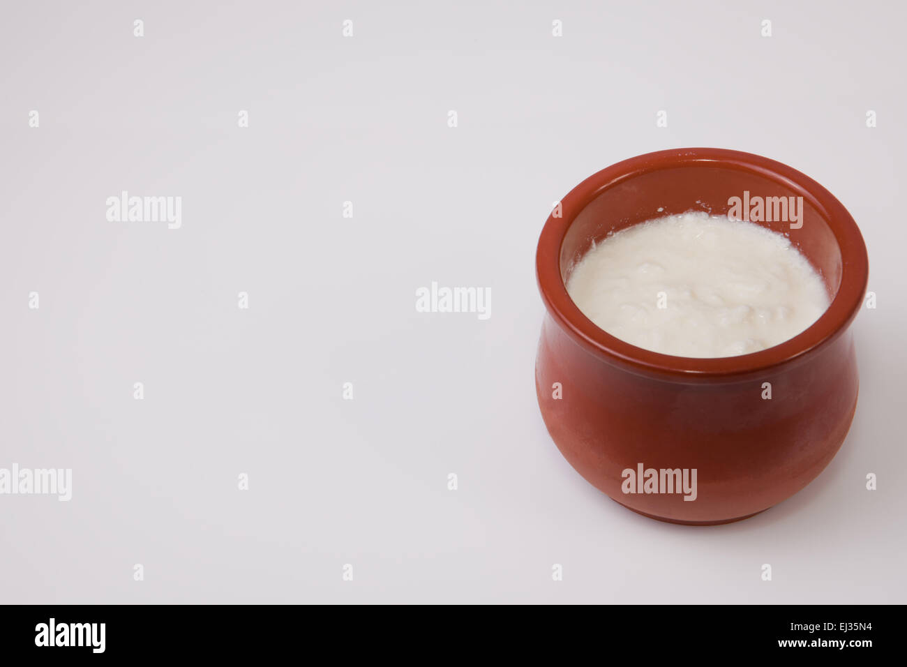 Homemade curd in clay pot made from cow milk. Isolated over white background Stock Photo