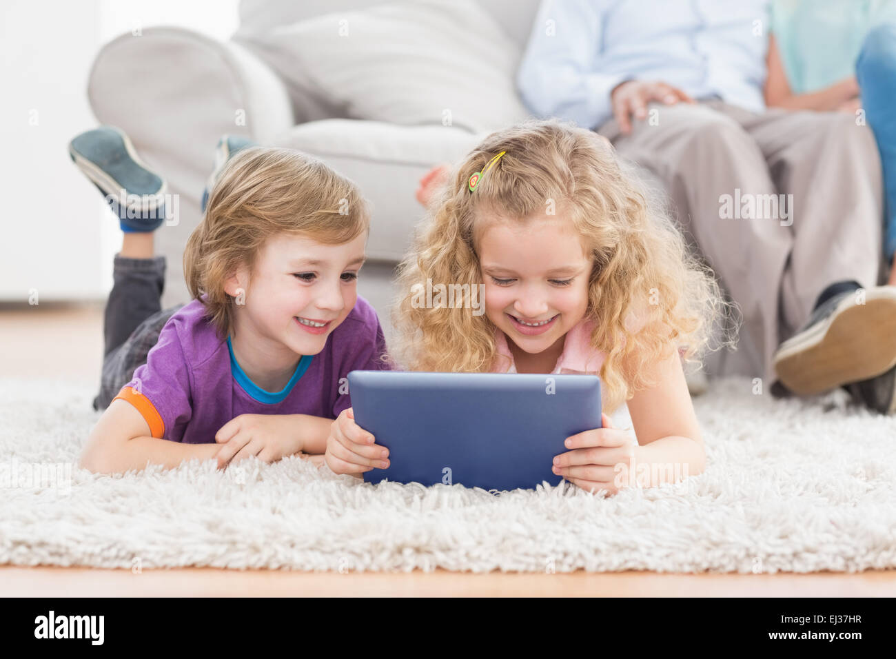 Brother and sister using digital tablet on rug Stock Photo - Alamy