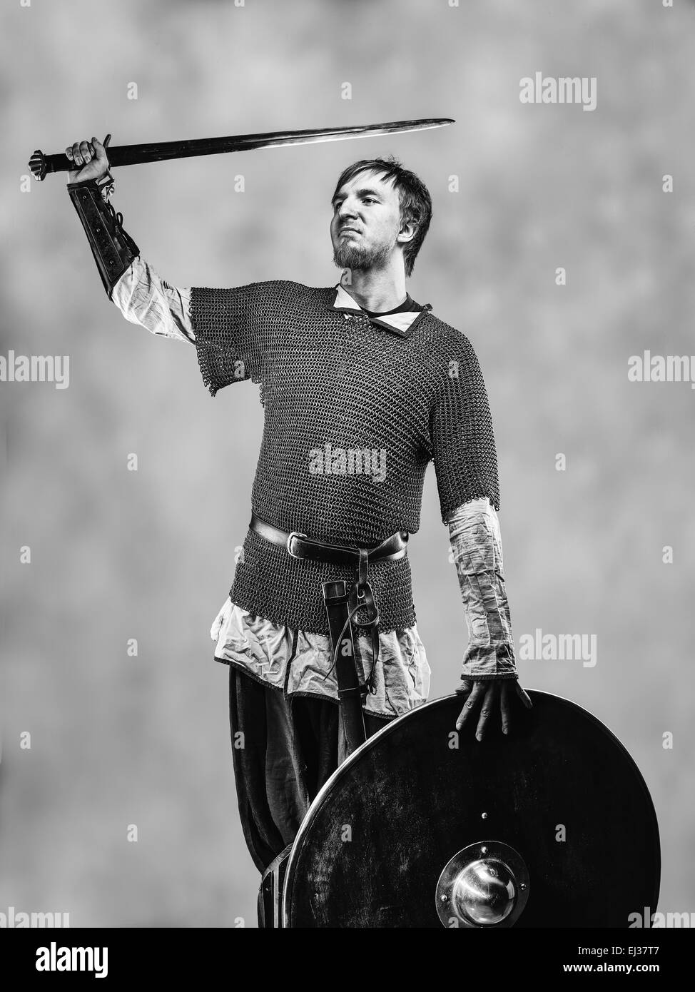 Victorious medieval knight armor with a sword and shield, black and white image Stock Photo